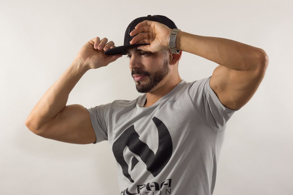 t-shirt personnalisé logo — Un homme stylé en casquette de baseball et T-shirt pose dans un cadre de studio.
