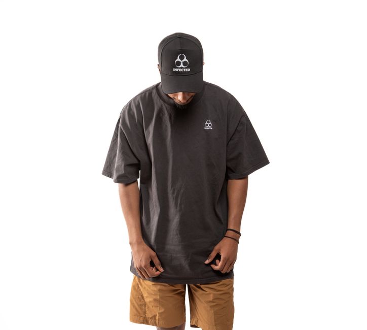 vêtement professionnel personnalisé — Modèle portant un t-shirt noir oversized et une casquette sur fond blanc.