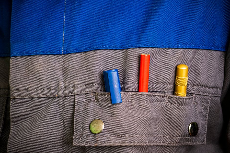 vêtement de travail sur mesure — Gros plan sur des outils colorés dans une poche de vêtement de travail bleue et grise.