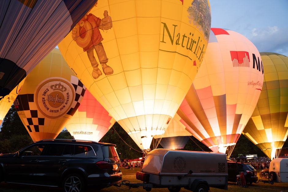 cadeau d'entreprise sur mesure — Des montgolfières colorées illuminées par la lumière du soir lors d'un festival.