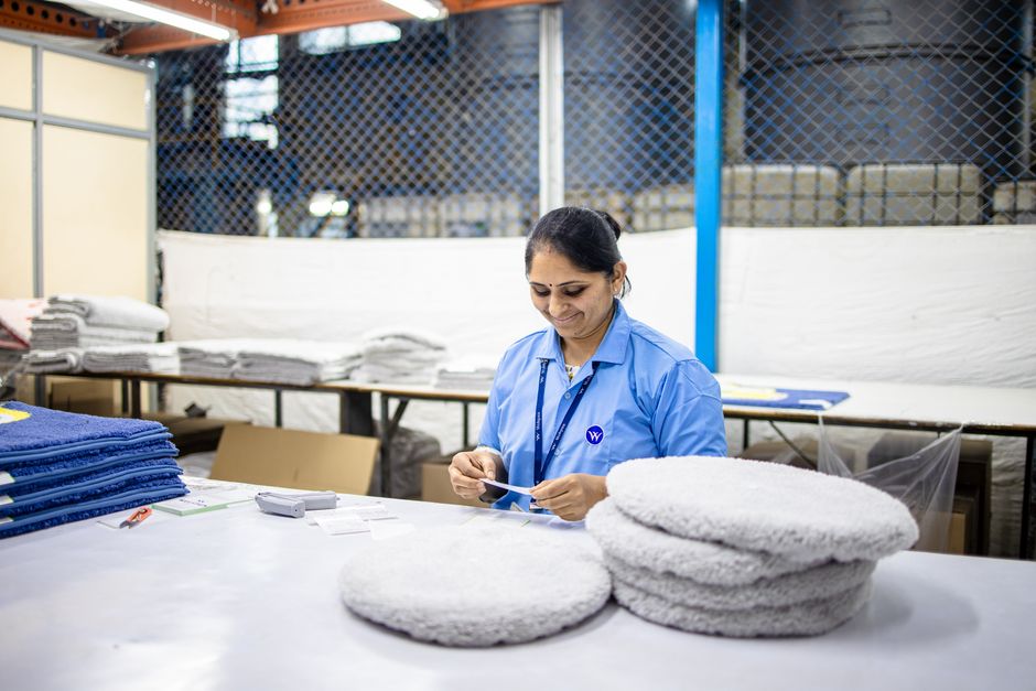 personnalisation de textiles — Un travailleur textile organise des tissus dans un environnement industriel.
