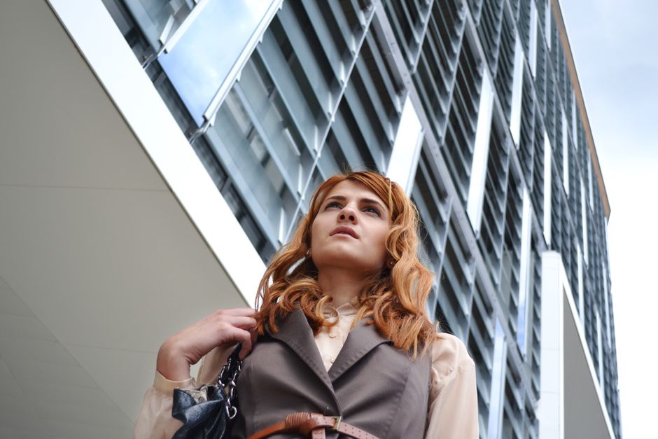 tenue de travail personnalisée — Une jeune femme à la mode posant avec confiance devant un bâtiment moderne en ville.